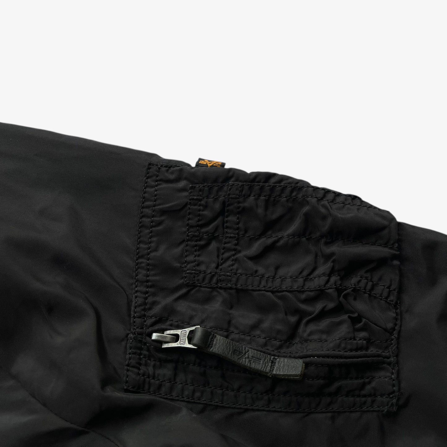Sleeve pocket of men's vintage Y2K Alpha Industries black bomber jacket.