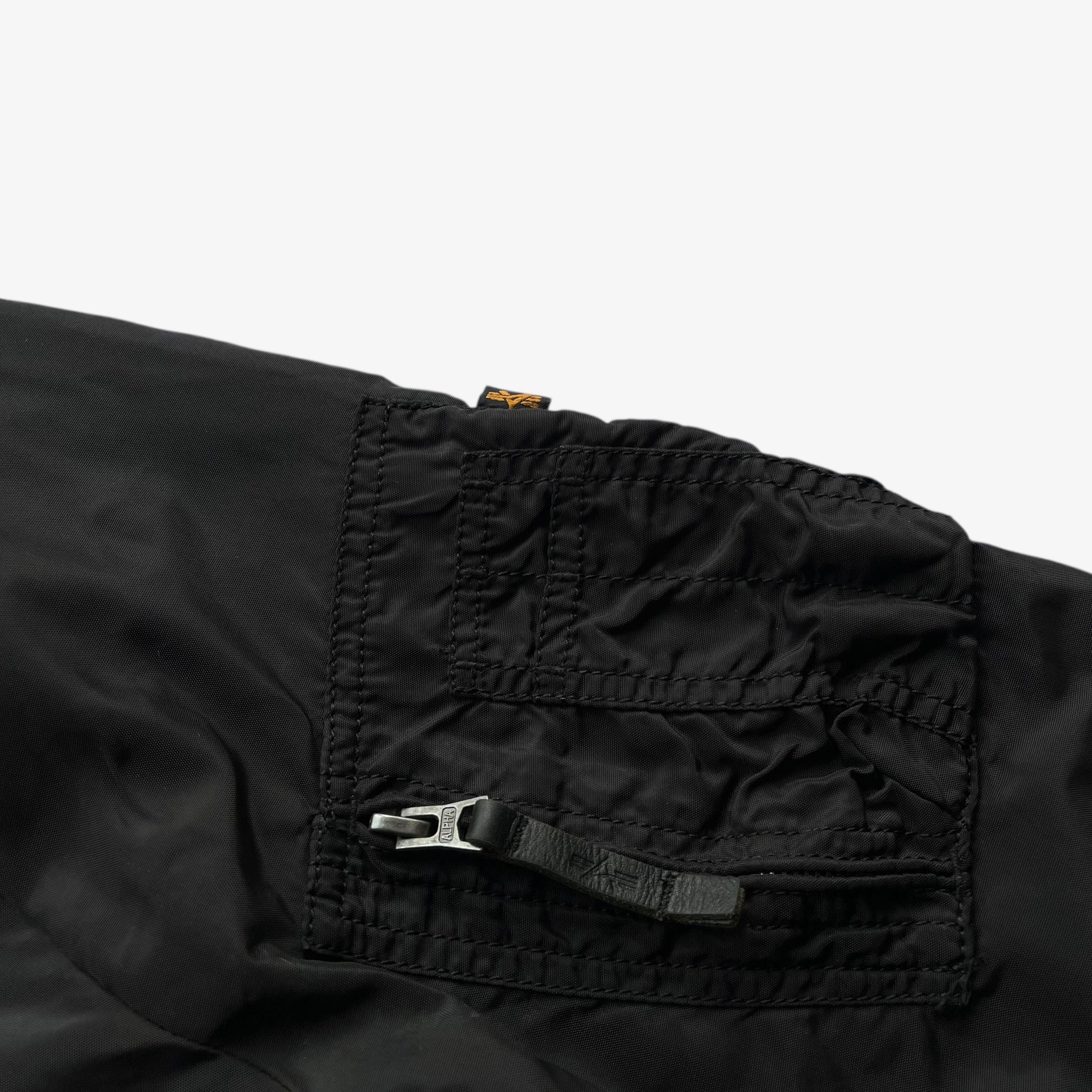 Sleeve pocket of men's vintage Y2K Alpha Industries black bomber jacket.