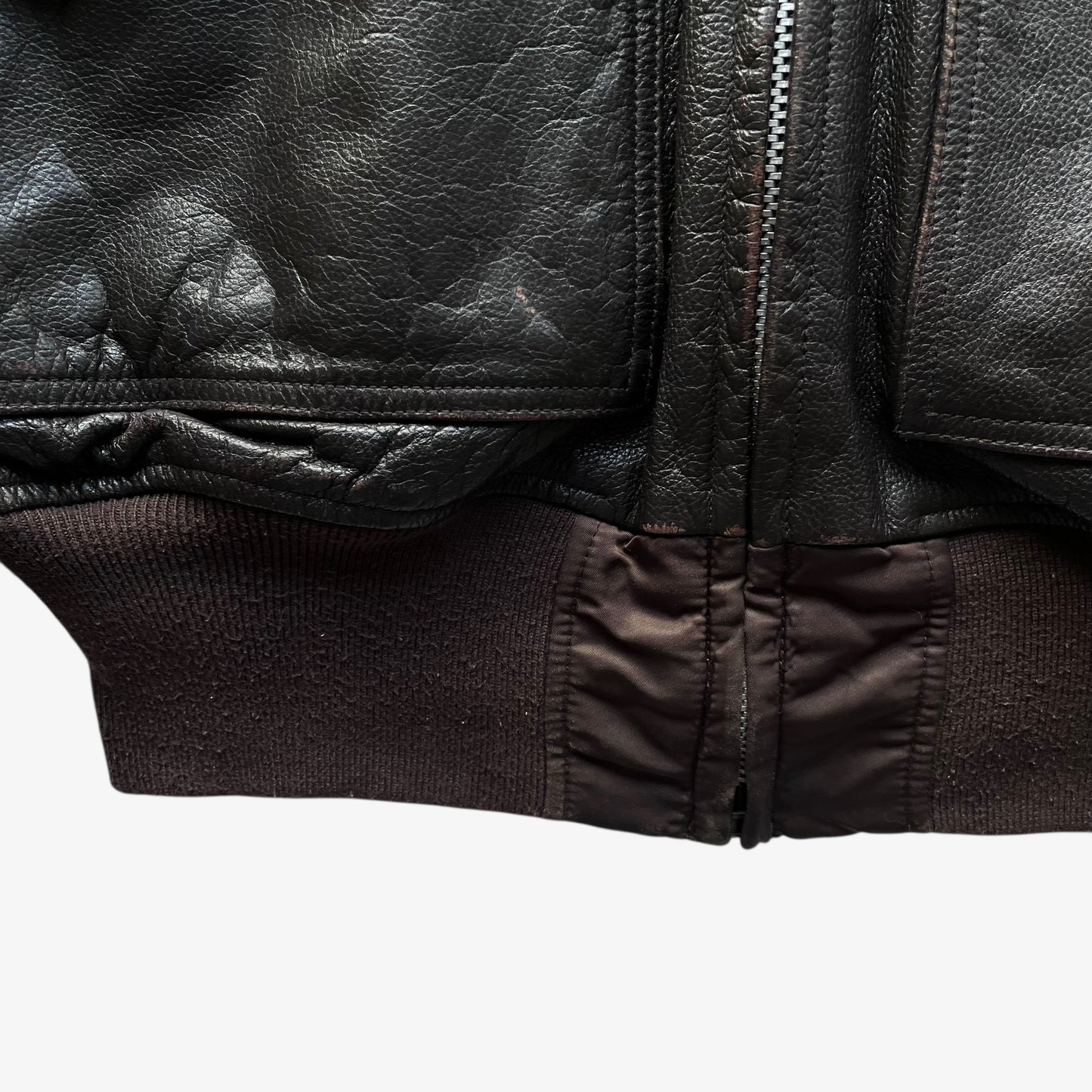 Hem of vintage Y2K men's Alpha Industries Breitling brown leather CWU-45 bomber jacket.