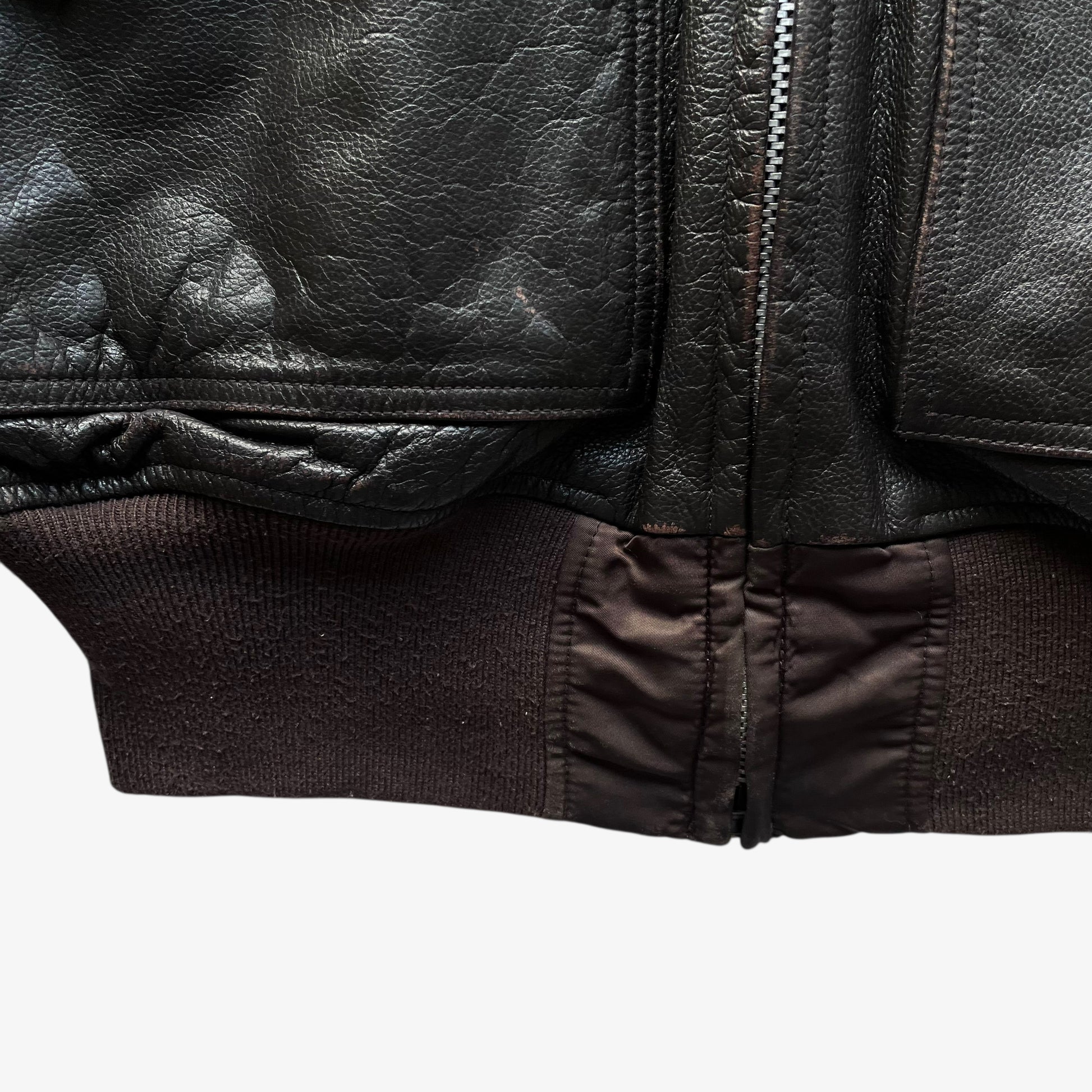 Hem of vintage Y2K men's Alpha Industries Breitling brown leather CWU-45 bomber jacket.