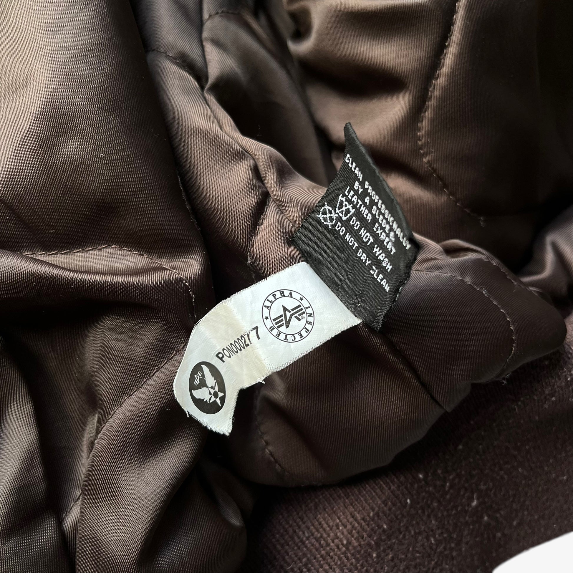 Inside label of vintage Y2K men's Alpha Industries Breitling brown leather CWU-45 bomber jacket.