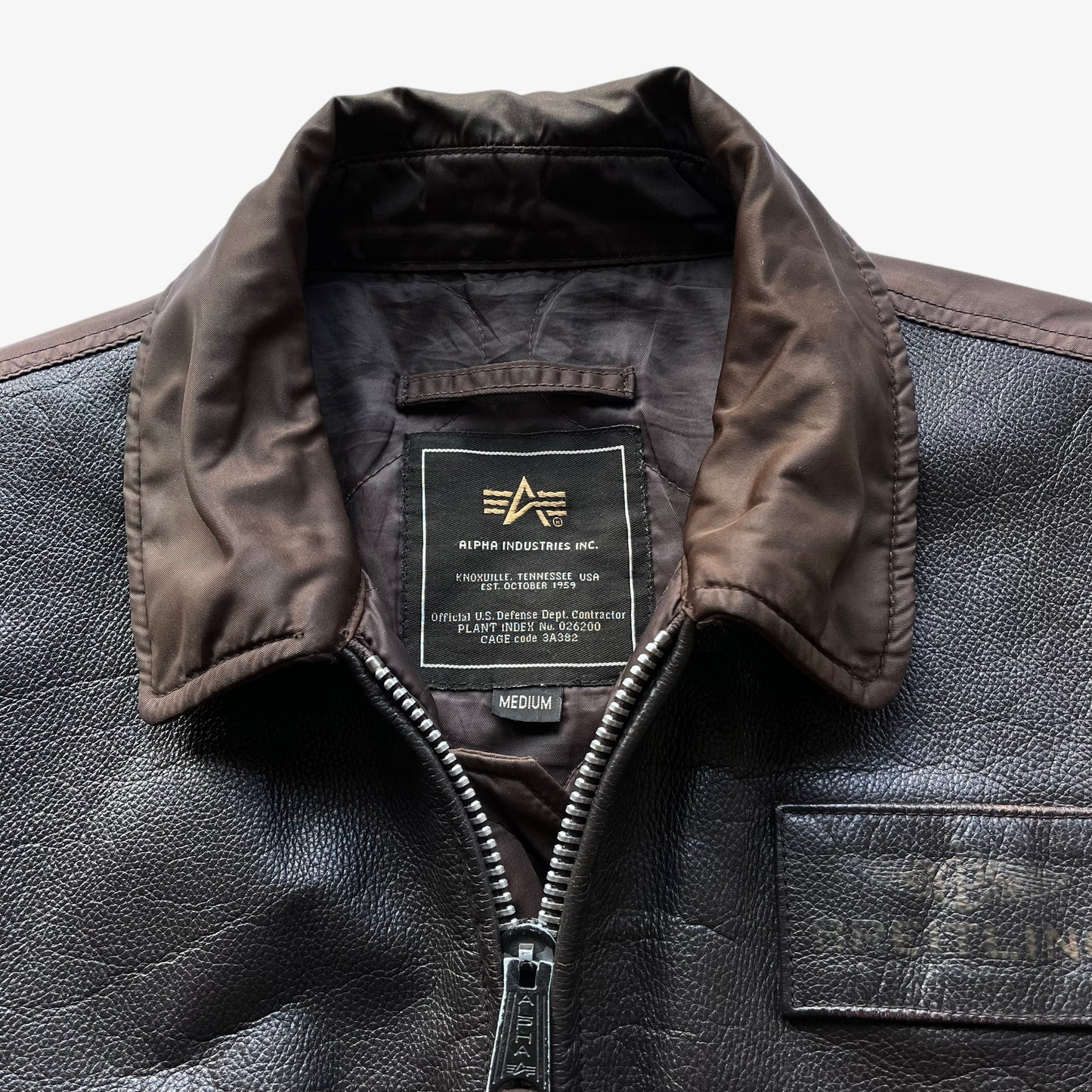 Alpha Industries label stitched inside of vintage Y2K men's Breitling brown leather CWU-45 bomber jacket.