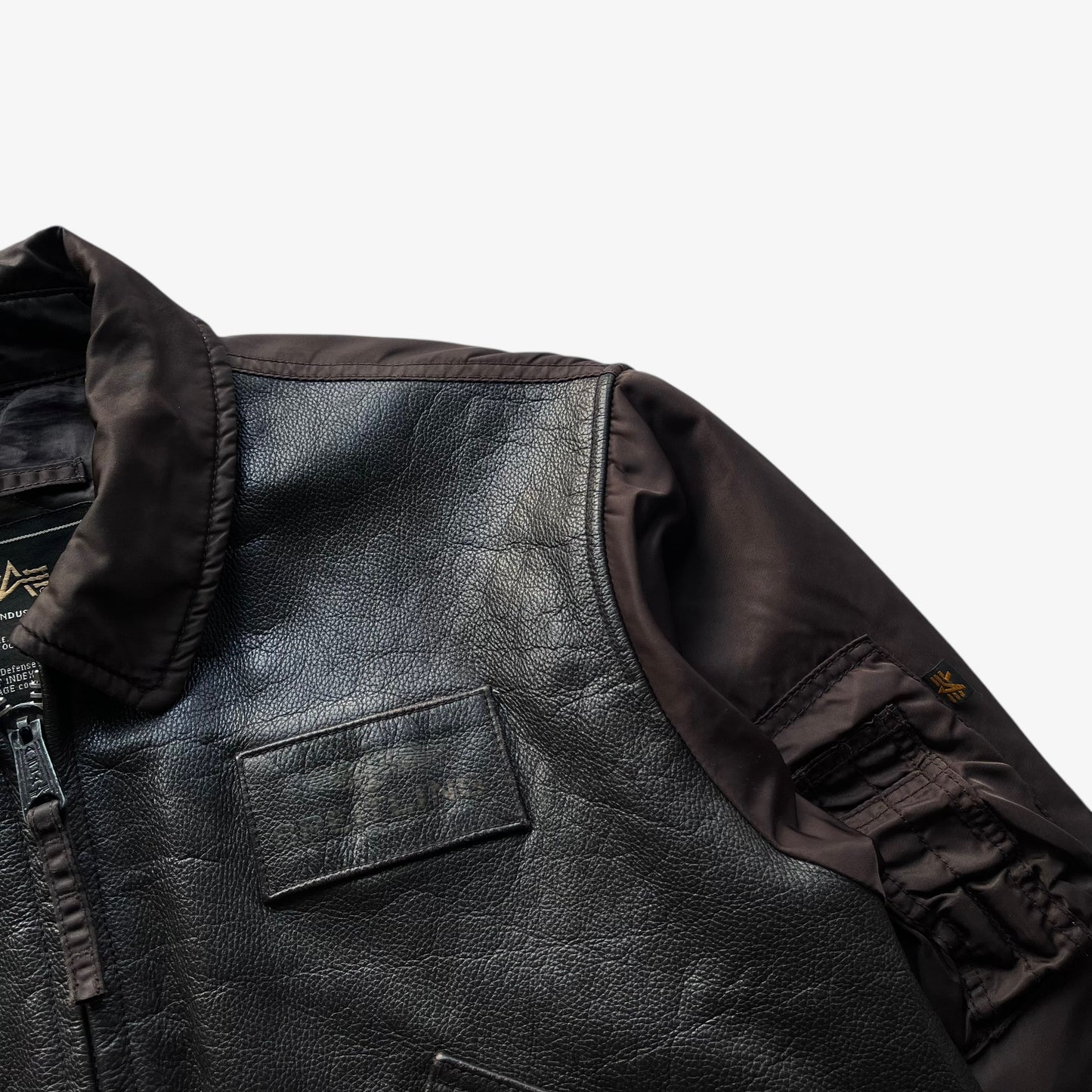 Printed badge logo on vintage Y2K men's Alpha Industries Breitling brown leather CWU-45 bomber jacket.