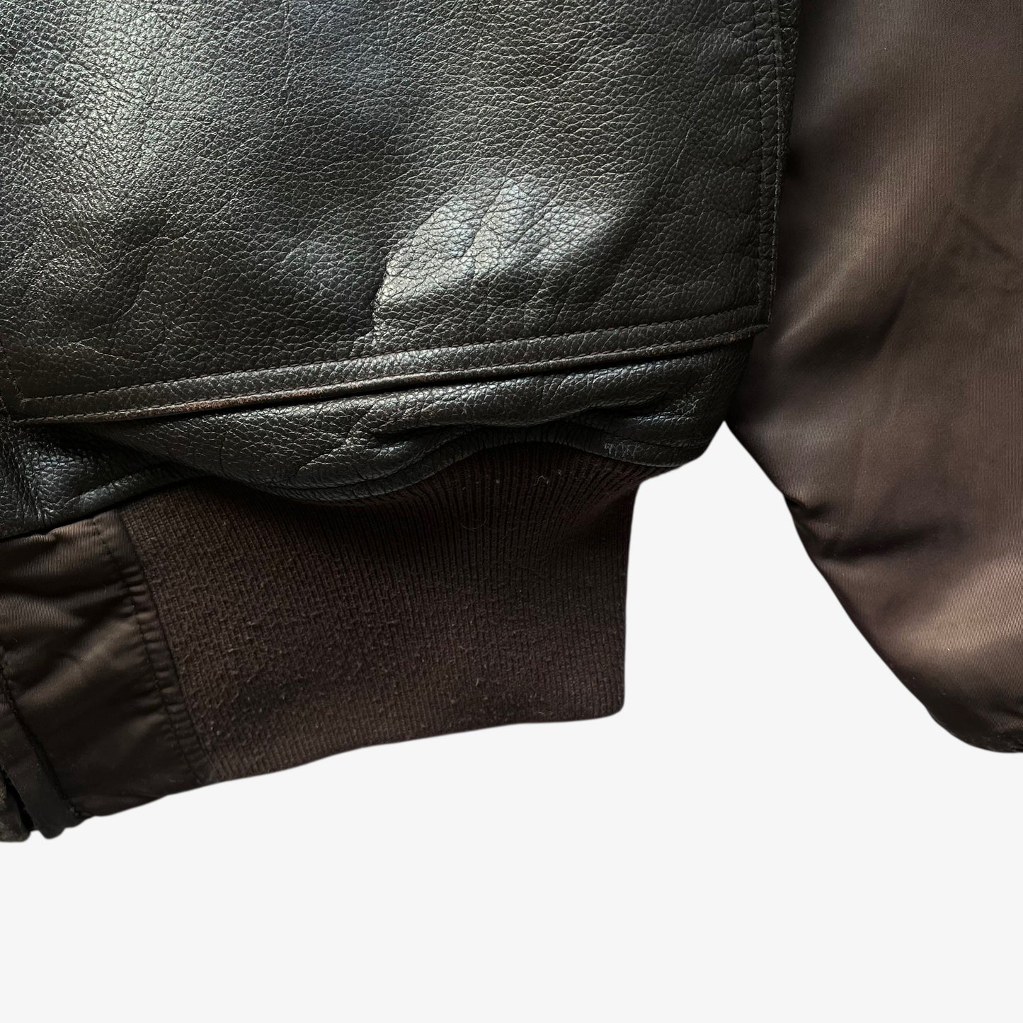 Ribbed hem of vintage Y2K men's Alpha Industries Breitling brown leather CWU-45 bomber jacket.
