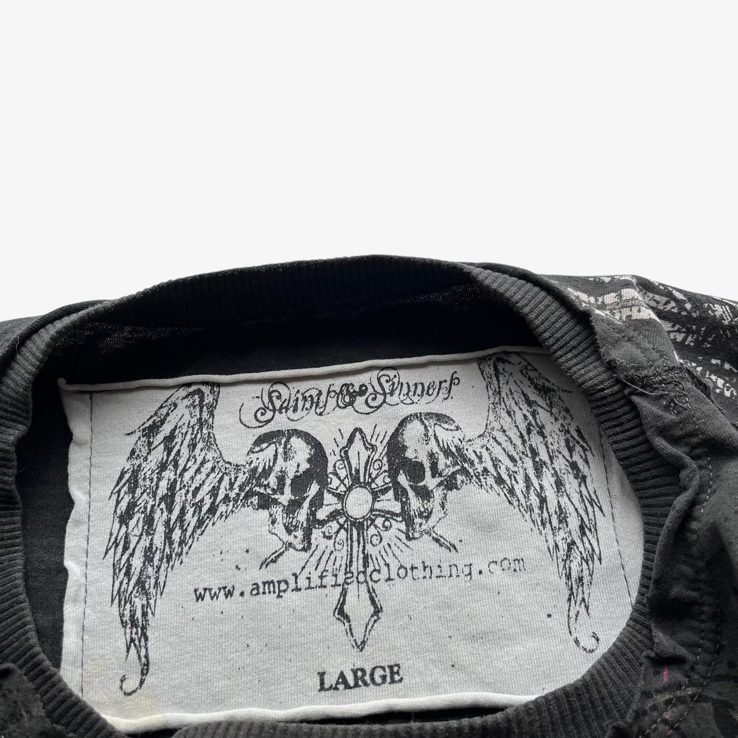 Amplified saints and sinners stitched label inside a vintage Y2K men's grey t-shirt.
