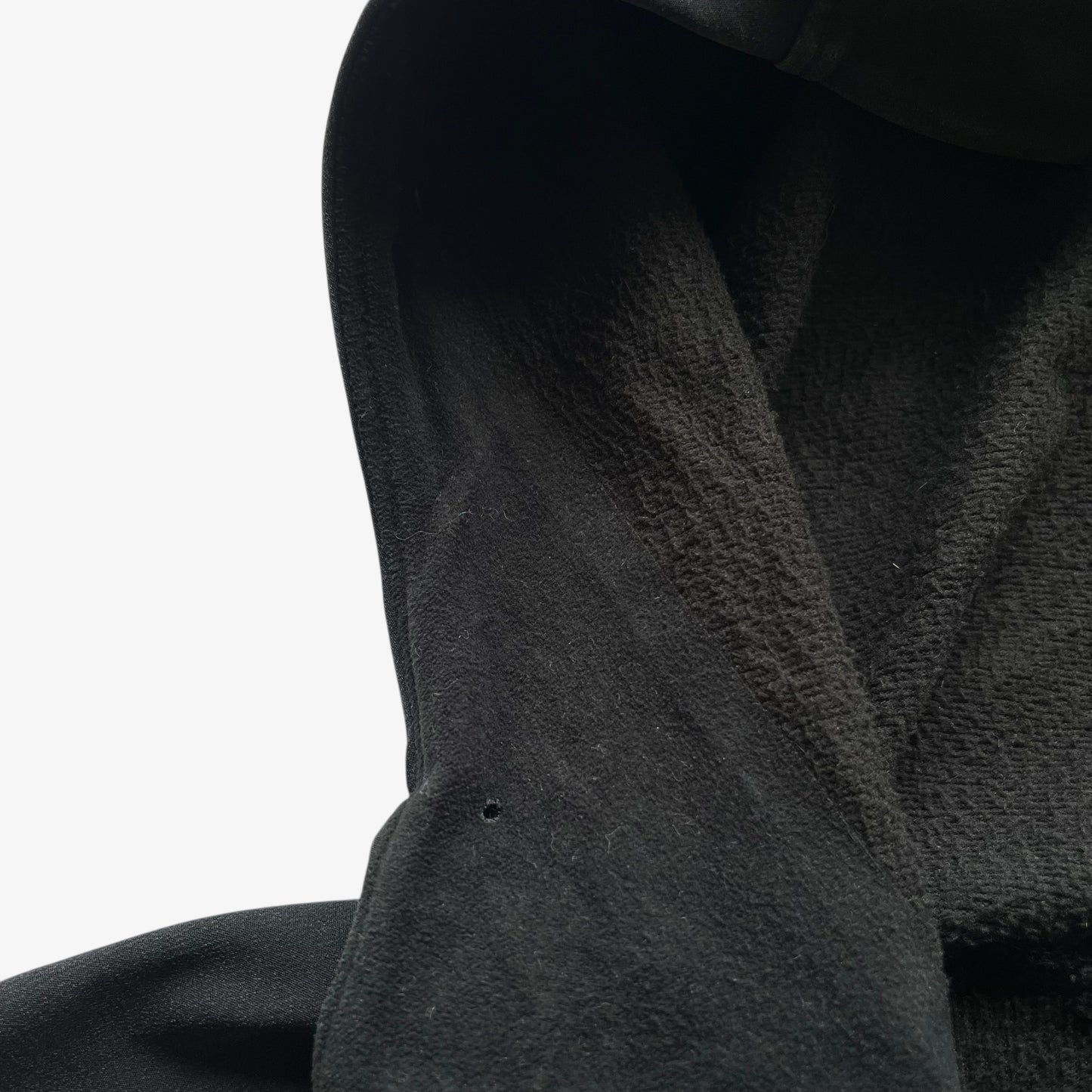 Patina on collar of men's vintage Y2K Arcteryx Polartec black hooded utility jacket.