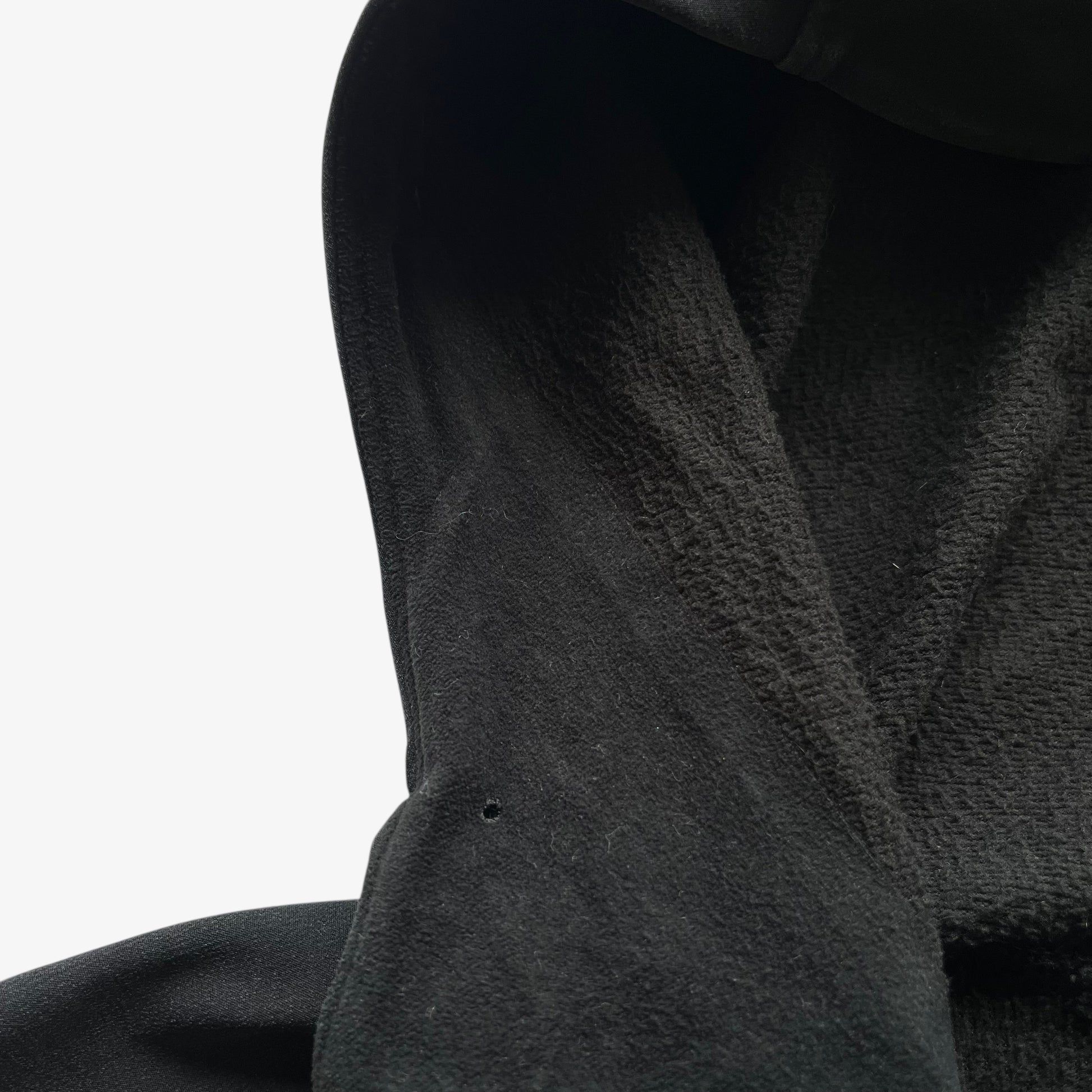 Patina on collar of men's vintage Y2K Arcteryx Polartec black hooded utility jacket.