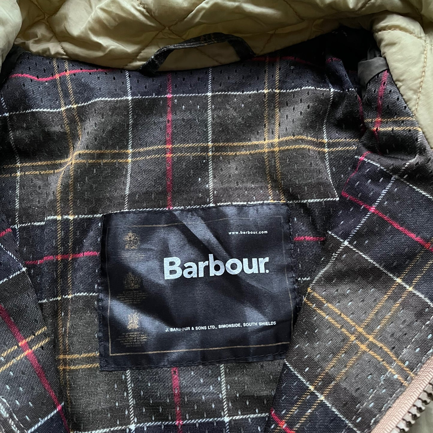 Barbour label stitched inside the tartan lining of a vintage Y2K men's lime green quilted jacket.