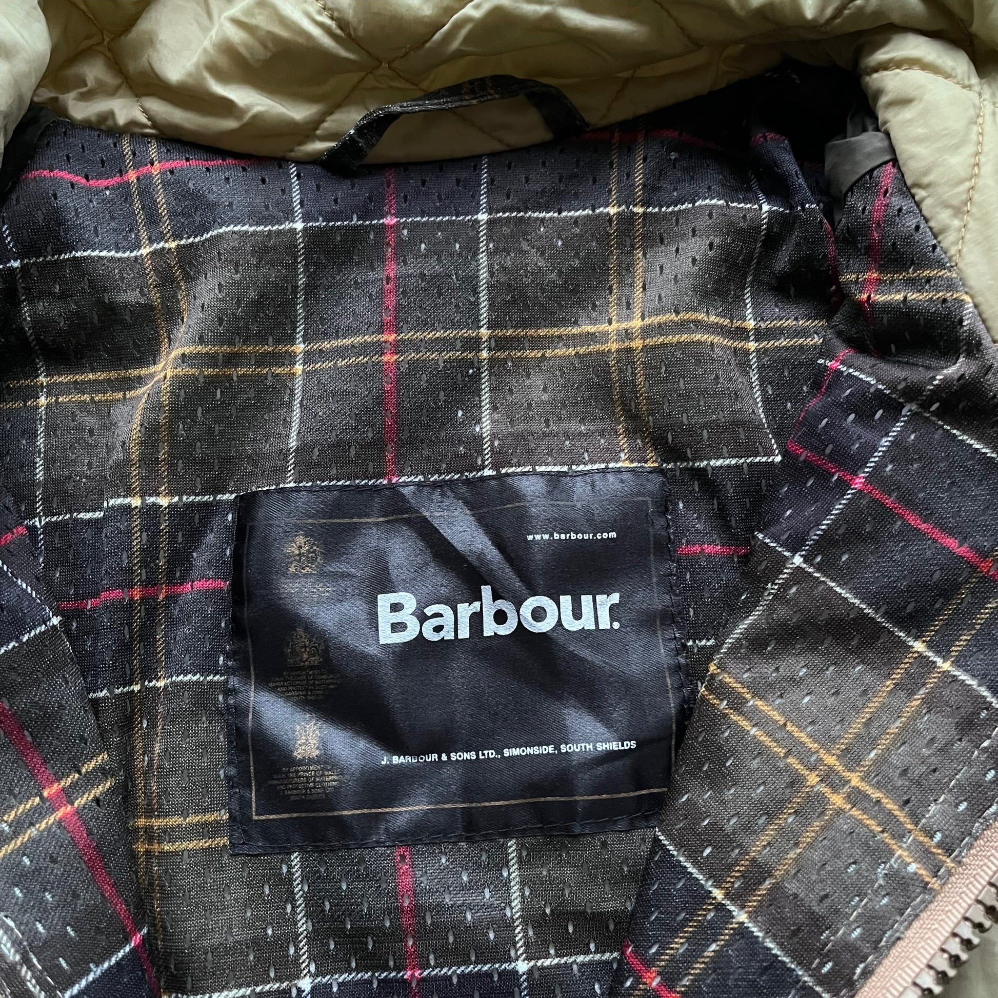 Barbour label stitched inside the tartan lining of a vintage Y2K men's lime green quilted jacket.