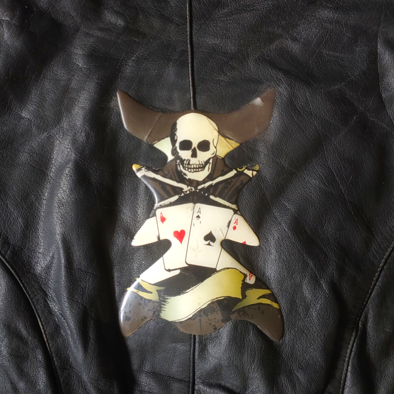Back design of black leather biker jacket with a skull and aces design.