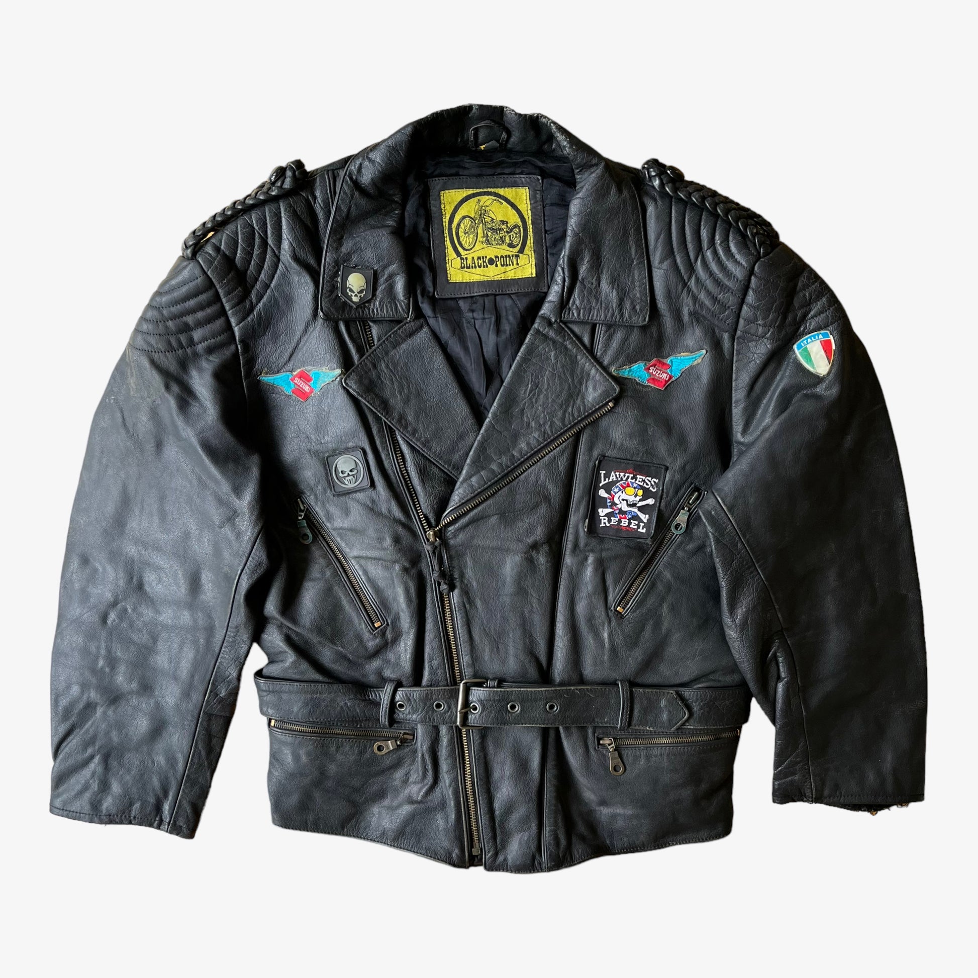 A black leather biker jacket with a skull and aces design on the back, featuring multiple zipped pockets and a belted waist.