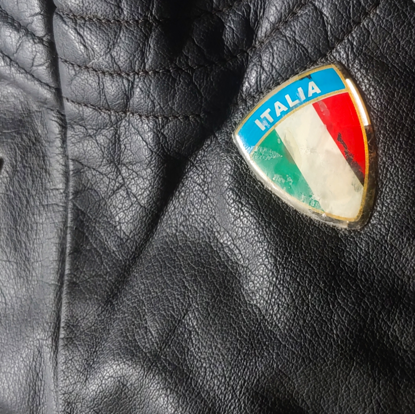 Italia badge on black leather biker jacket with a skull and aces design on the back.