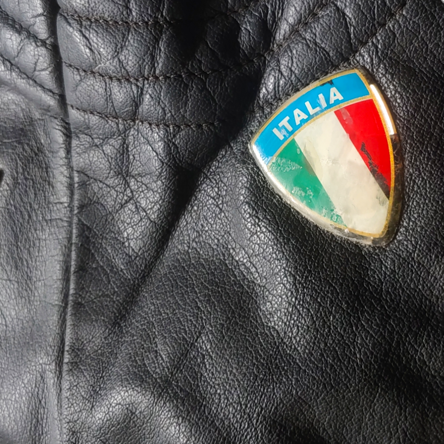 Italia badge on black leather biker jacket with a skull and aces design on the back.