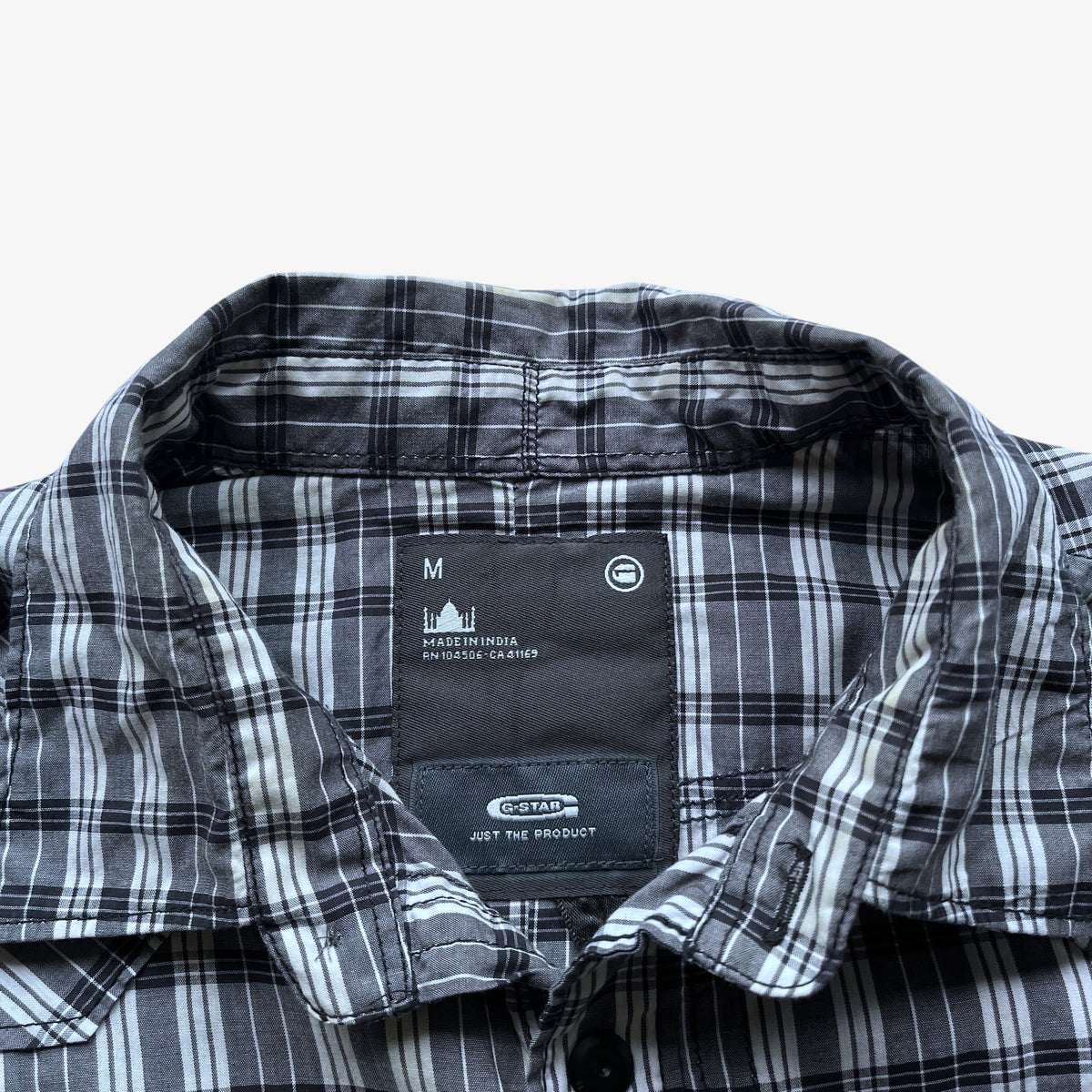 Close-up of a grey plaid button-down shirt collar, showing the inner neck label with size M and G-Star branding.