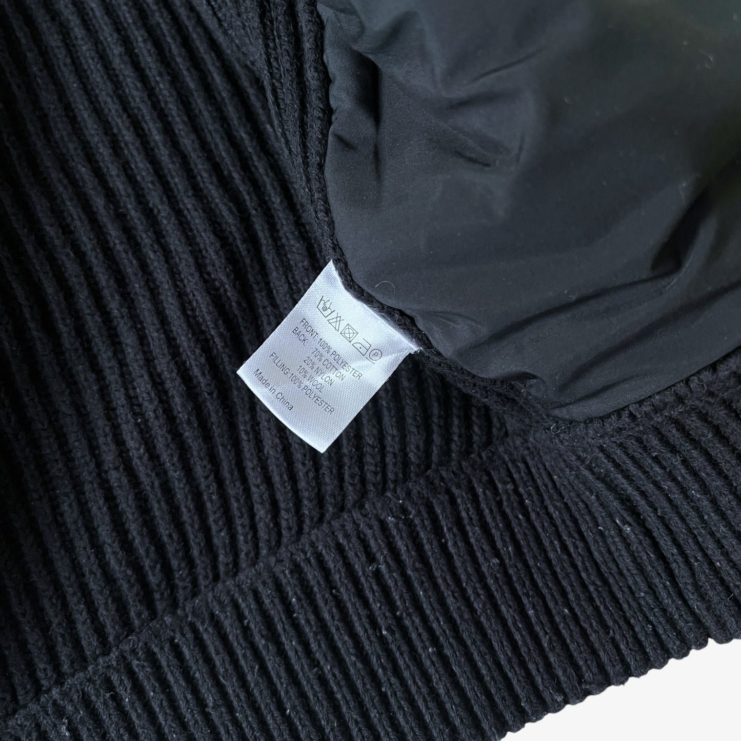 Close up of inside label stitched inside a vintage black ribbed wool blend gilet.