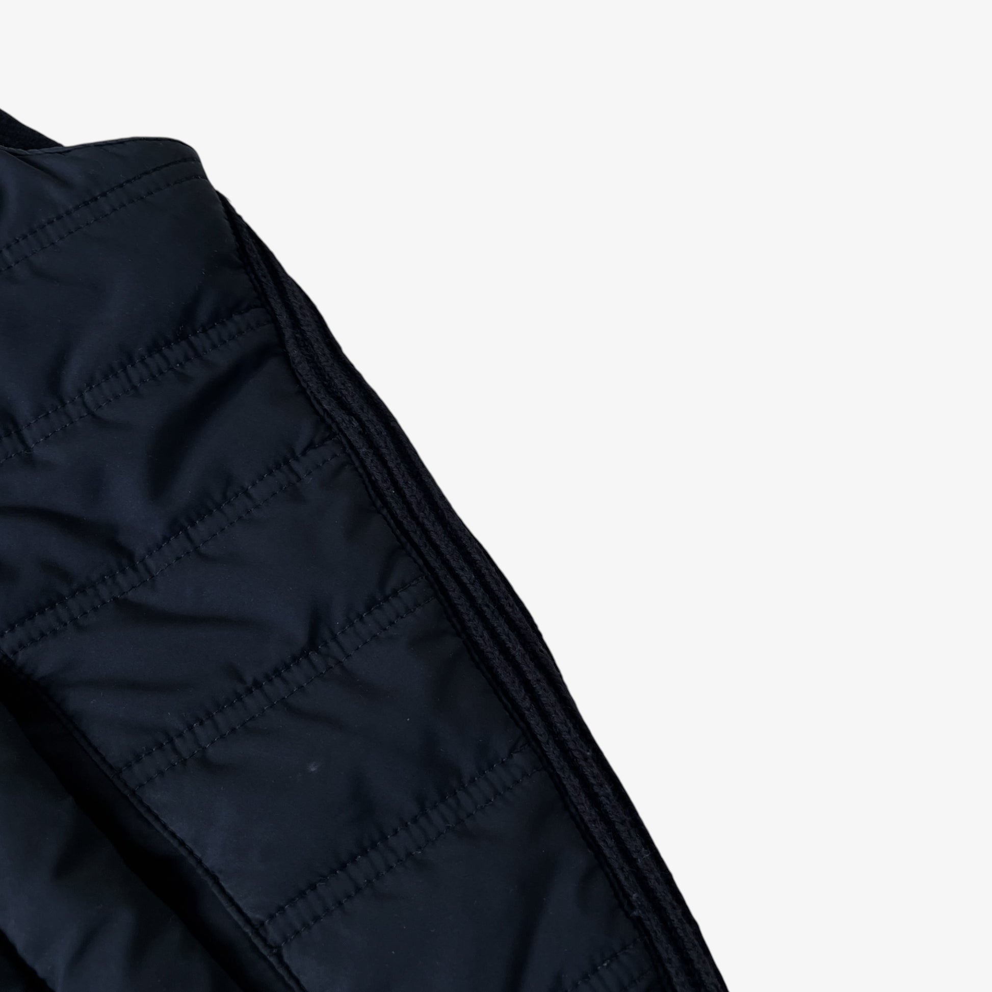 Close up of patina on a vintage Y2K Hawes and Curtis black quilted puffer gilet.