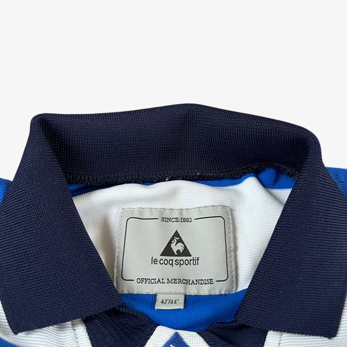 Close-up of a vintage Le Coq Sportif label on a 2001 QPR jersey with navy collar.