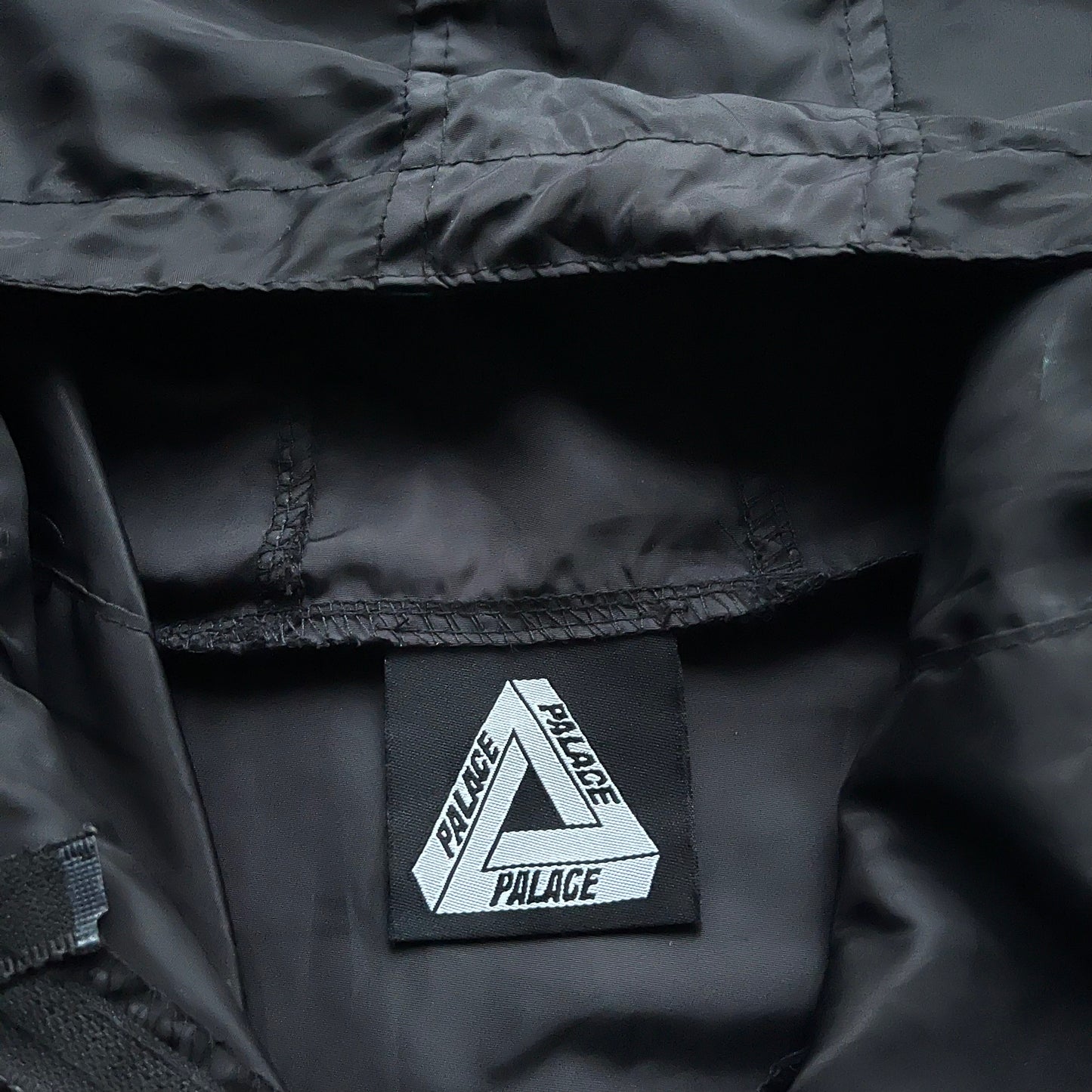 Palace label stitched inside of men's vintage Y2K spell out print black hooded jacket.