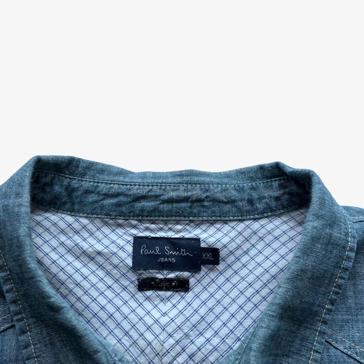 Vintage Y2K Paul Smith jeans label stitched inside a men's blue denim shirt.