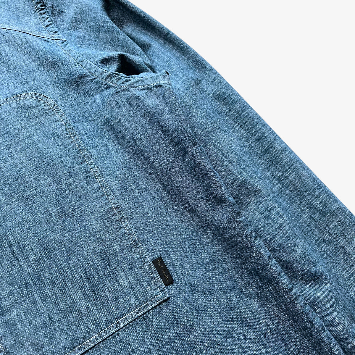 Paul Smith tag stitched on the pocket of a vintage men's denim shirt.