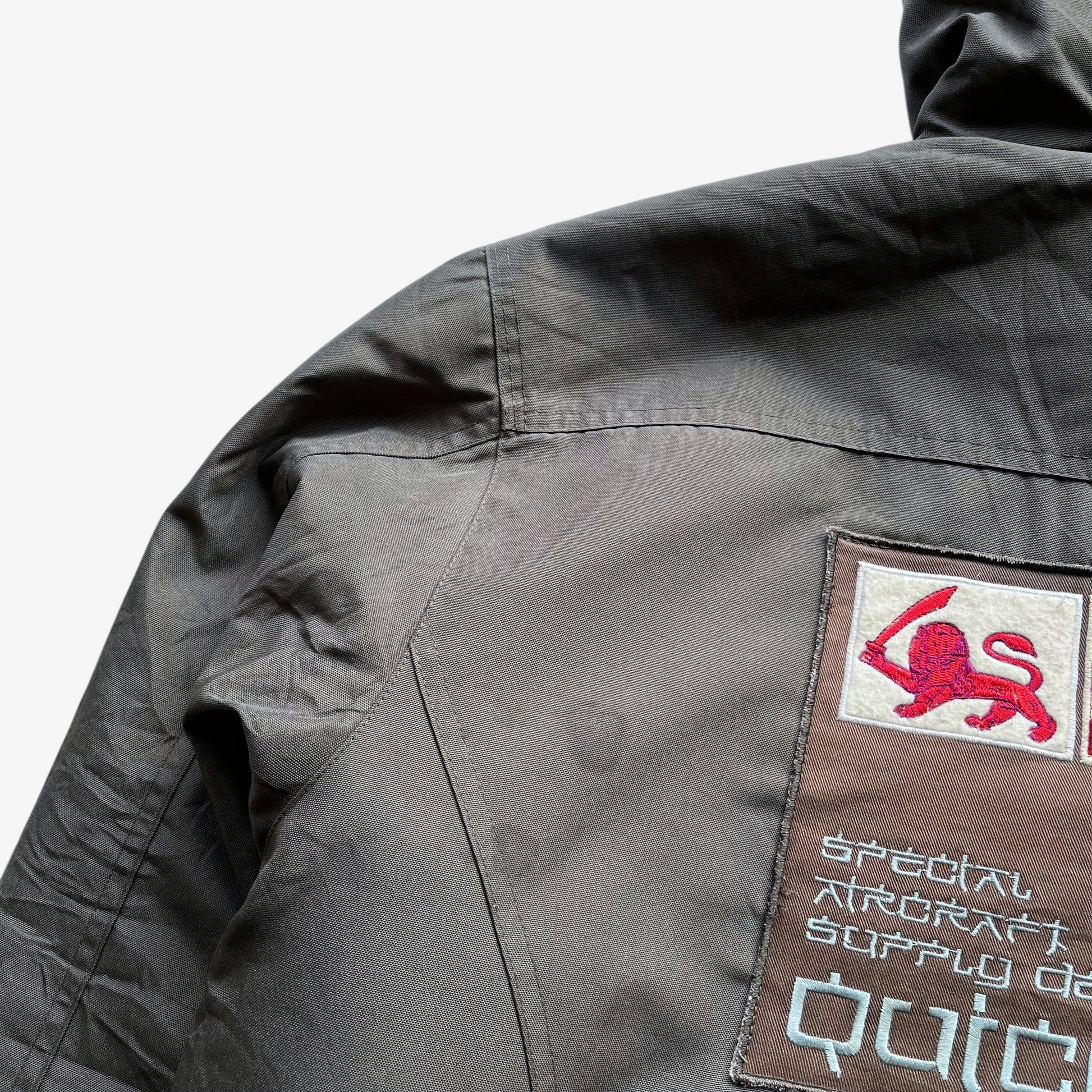 Patina on men's vintage Y2K Quickshark special aircraft supply grey utility jacket with back spell out.
