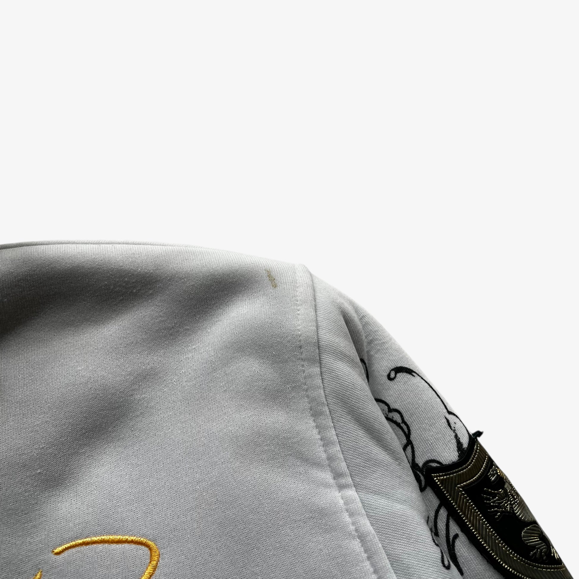 Patina on shoulder of vintage Y2K men's Really Point skull and snake double sided print white hooded jacket with sherpa lining.