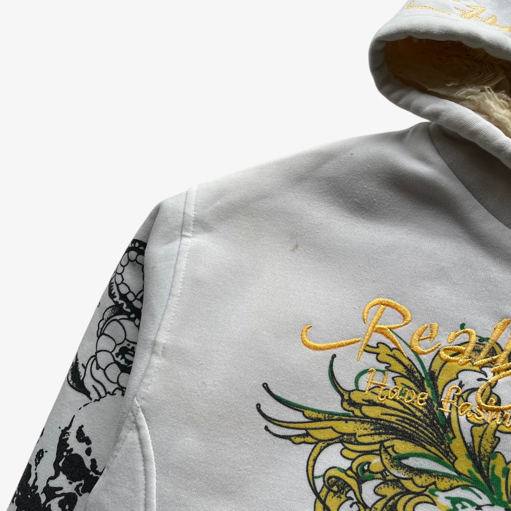 Wear on shoulder of vintage Y2K men's Really Point skull and snake double sided print white hooded jacket with sherpa lining.