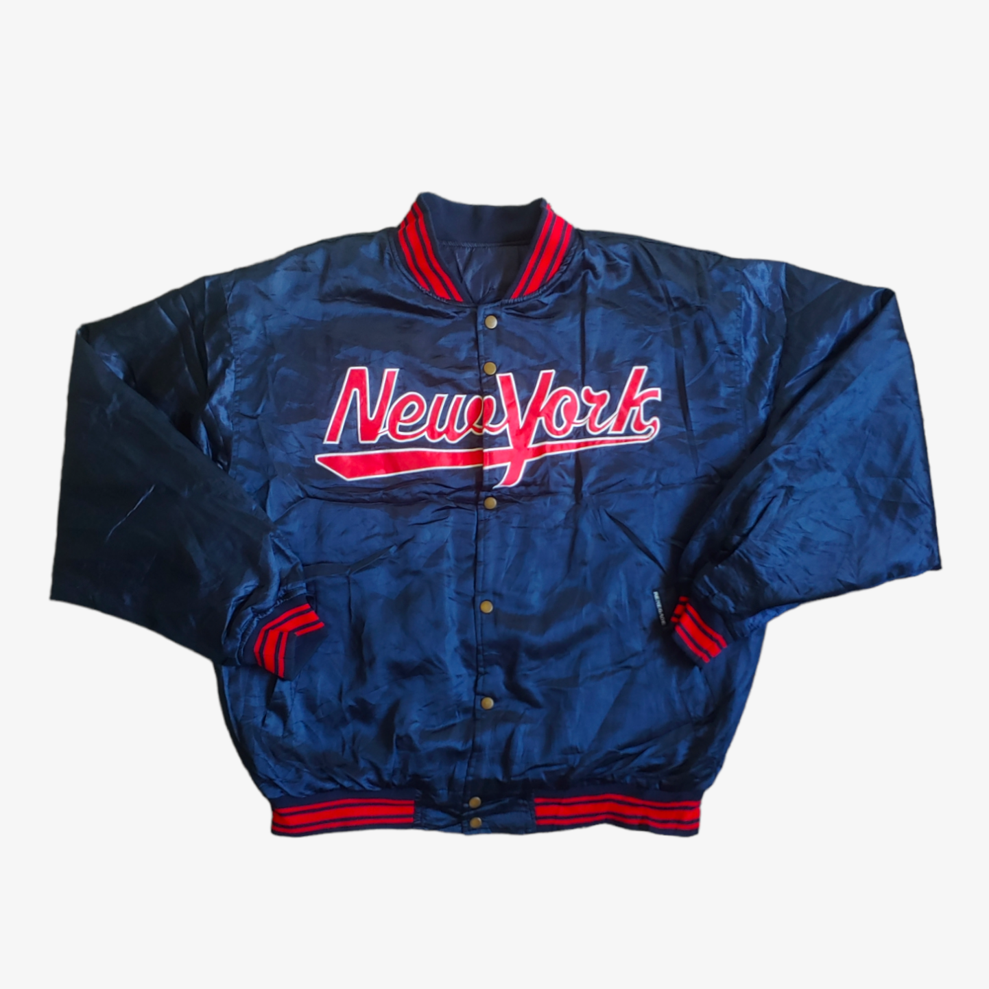A navy blue and red Renegade New York embroidered spell out varsity jacket with two side pockets and a collar.
