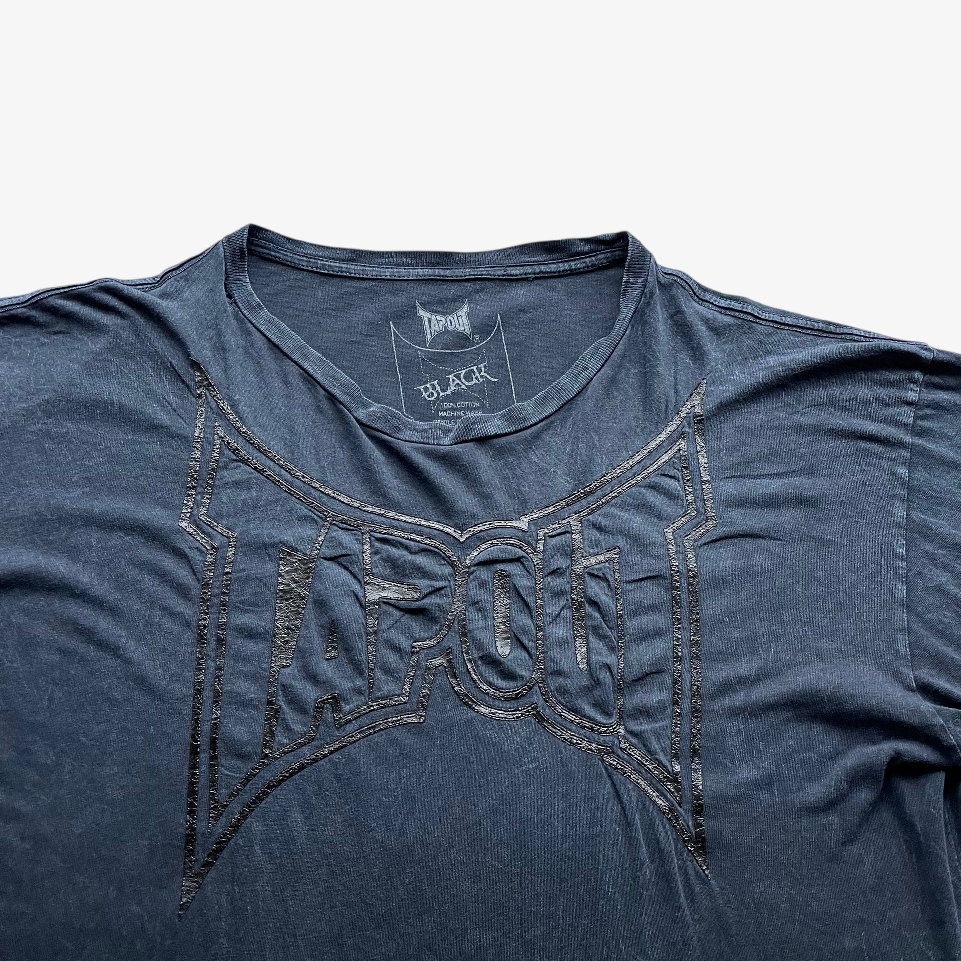 Close up of a 3D embossed Tapout spell out on a vintage men's navy t-shirt.