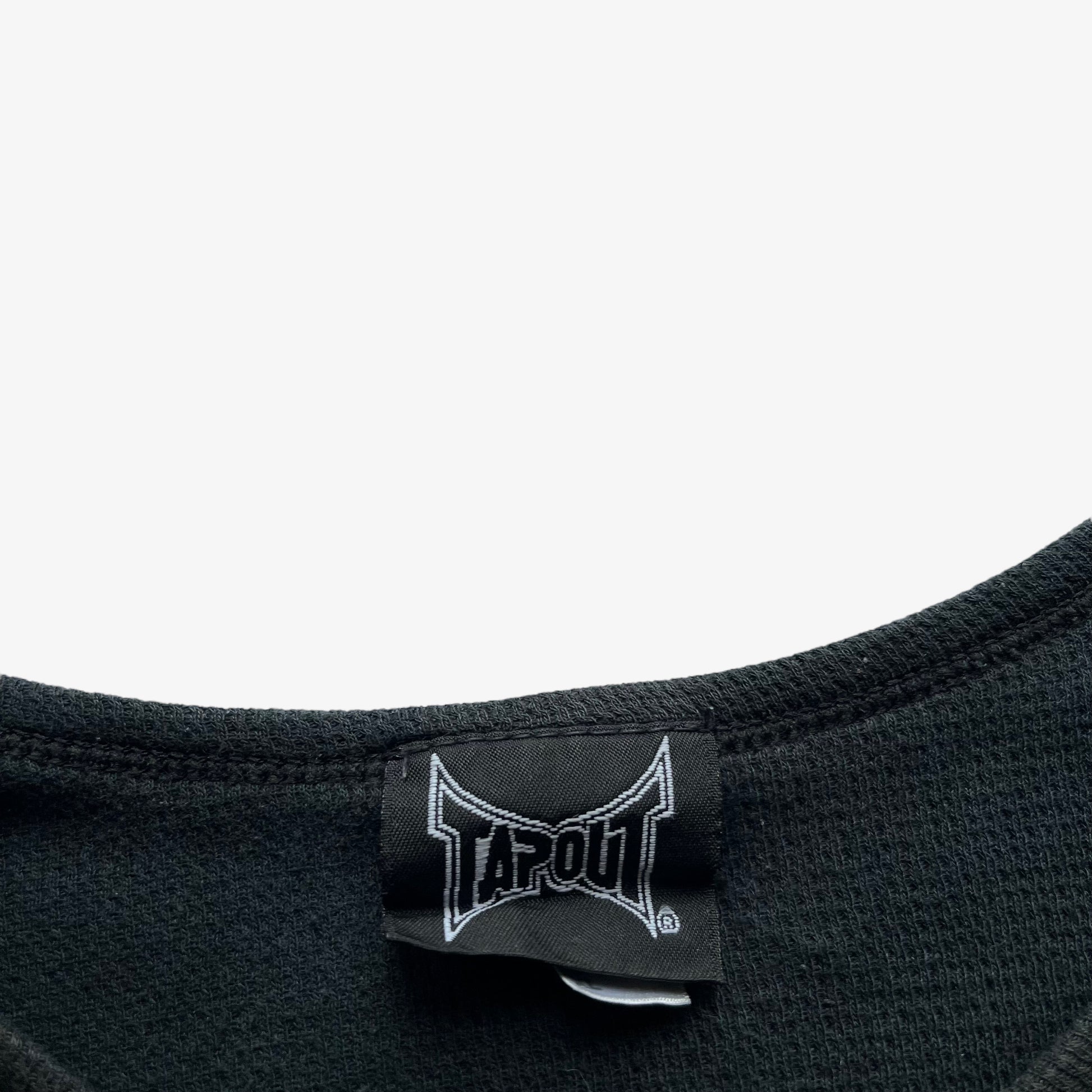 Close up of Tapout label stitched inside of a faded grey vintage long sleeve t-shirt.