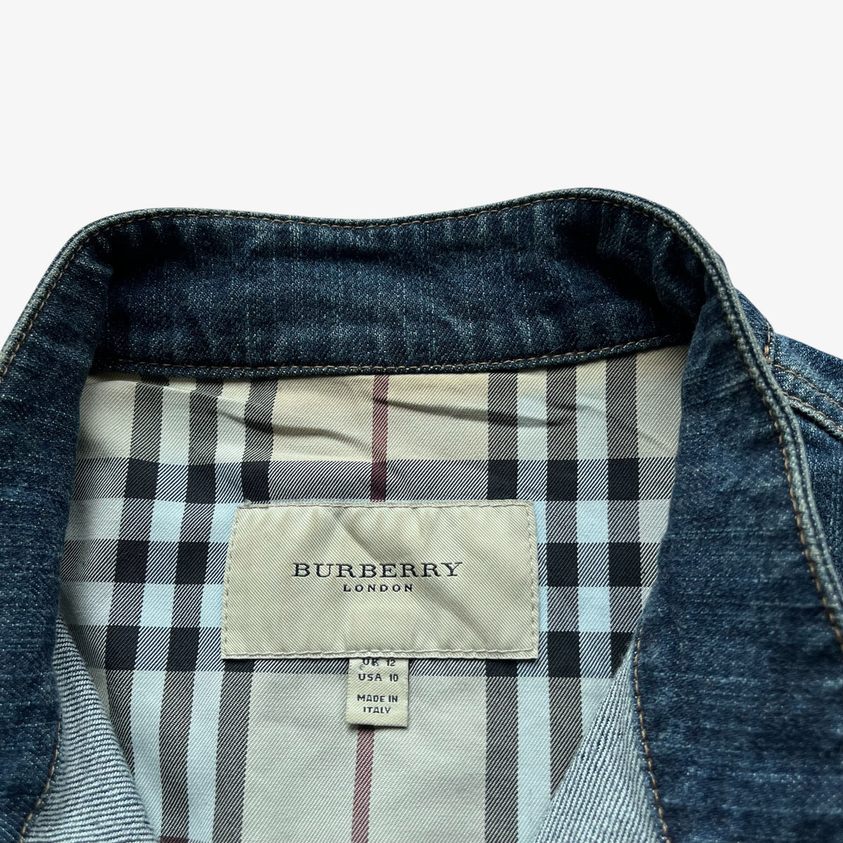 Close-up of a Burberry London denim jacket collar showing the dark blue denim fabric and the classic nova check lining, with the Burberry brand label clearly visible.