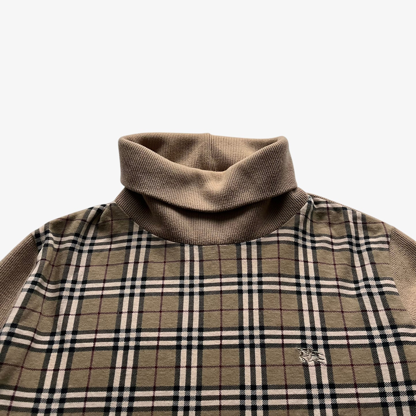 Close up of knight embroidered logo on a vintage Y2K women's Burberry cotton turtleneck jumper featuring a nova check stripe.