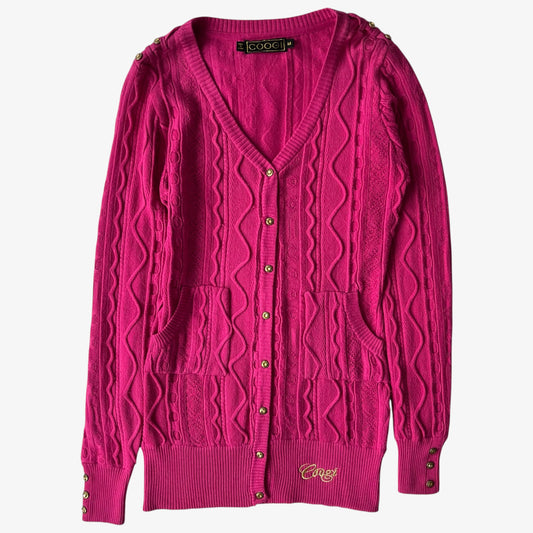 Vintage Coogi pink women's cardigan with cable knit pattern on a white background.