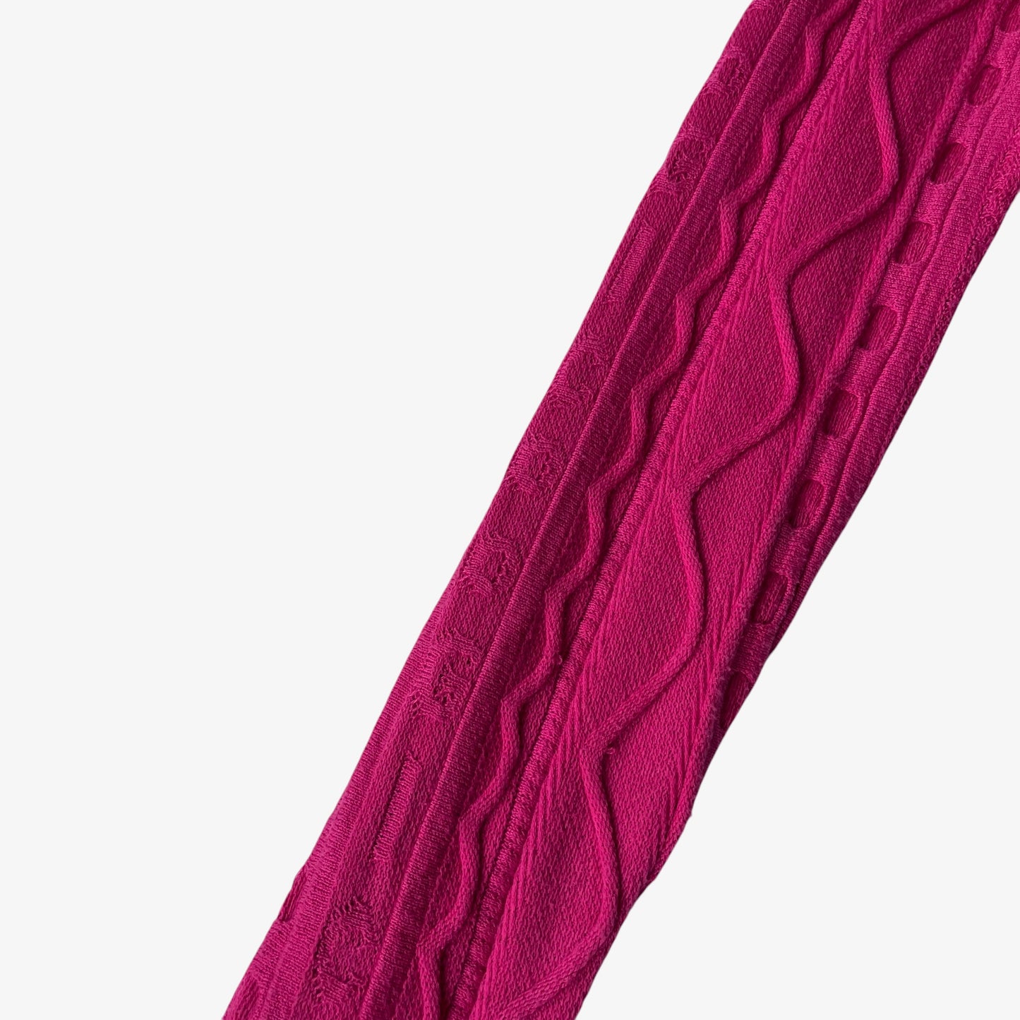 Close up of a pink knitted cardigan sleeve with Coogi spell out.