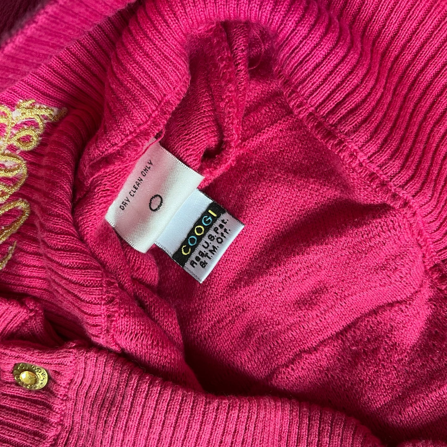 Close up of a pink sweater with a vintage Coogi label on it.