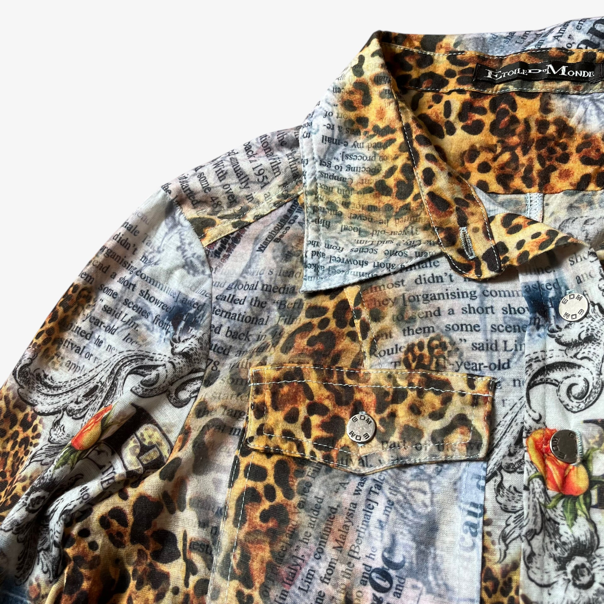 Engraved logo buttons on a vintage Y2K women's Etoile Du Monde leopard and newspaper print shirt.