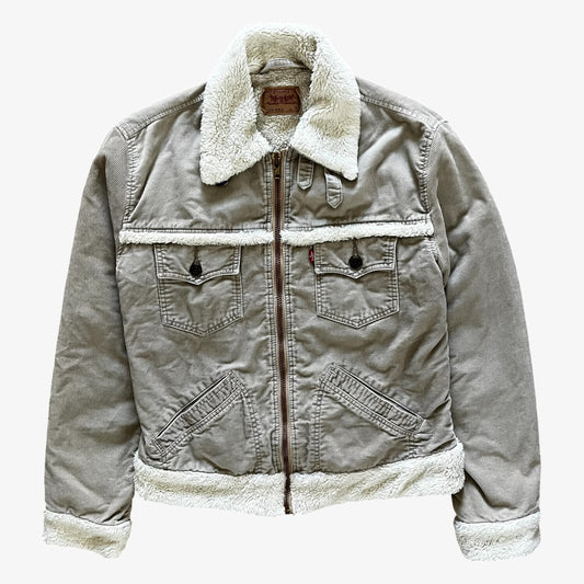 A Levi's beige corduroy jacket with a white sherpa lining, featuring a front zipper, two chest pockets with button flaps, and a classic collar, shown against a plain light grey background.