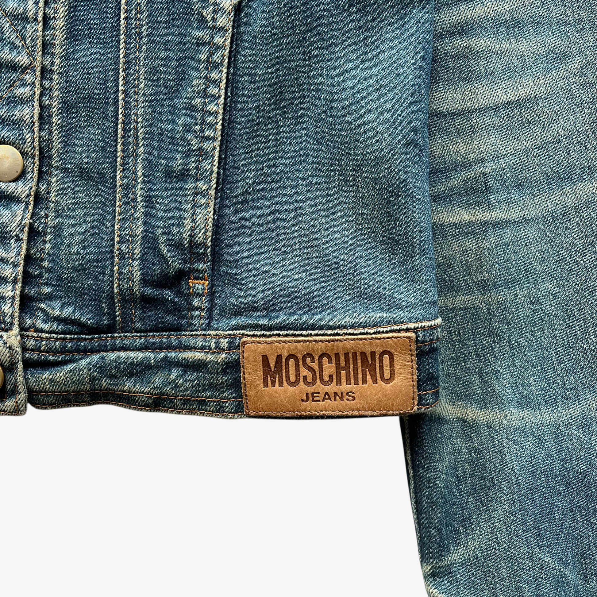 Moschino jeans leather brand tag on vintage Y2K women's blue denim trucker jacket.