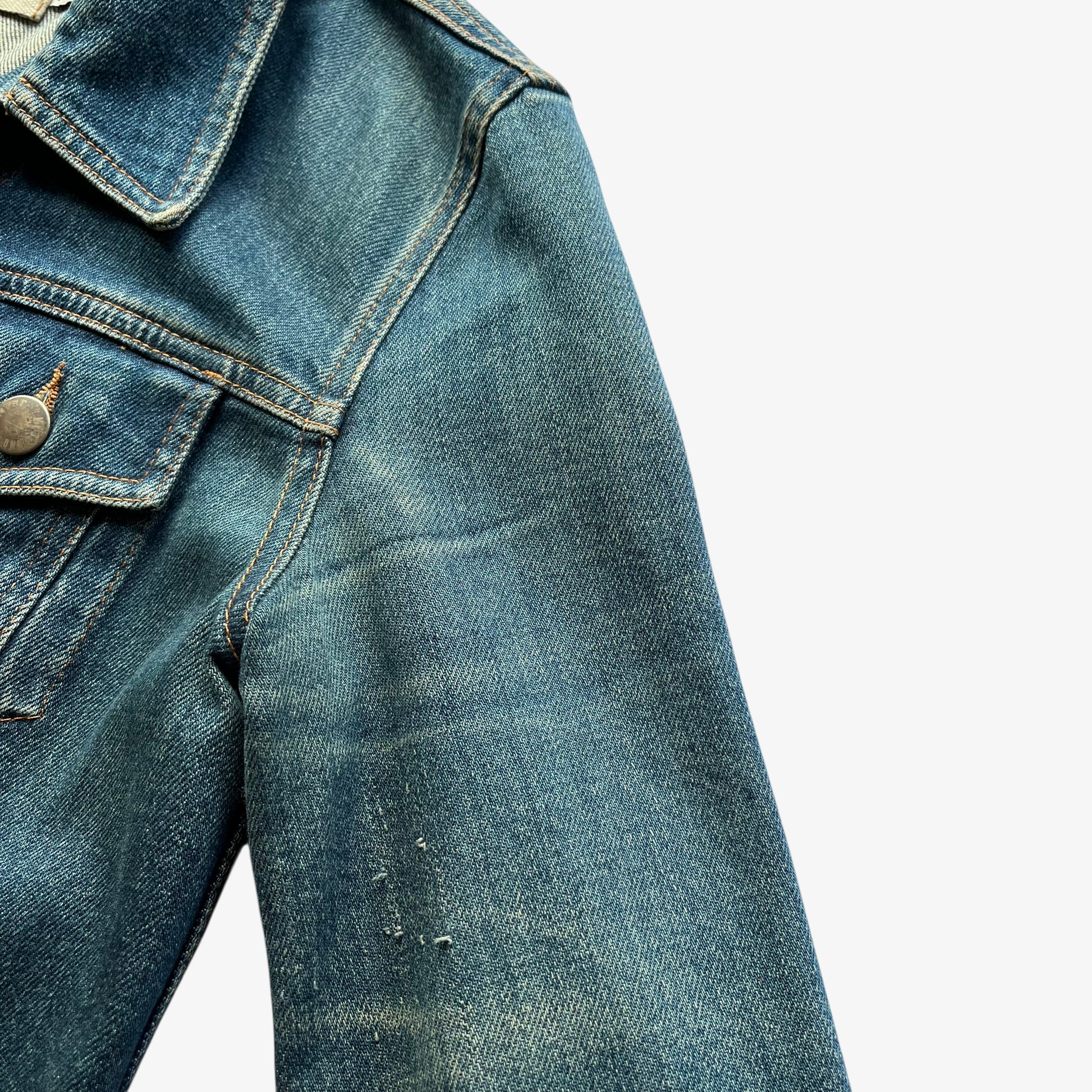 Patina on vintage Y2K women's Moschino jeans blue denim trucker jacket.