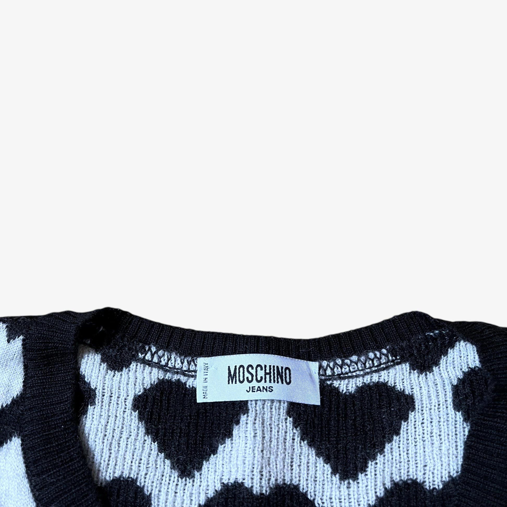 Label of vintage Y2K Moschino Jeans women's black and white v-neck wool jumper with heart pattern.