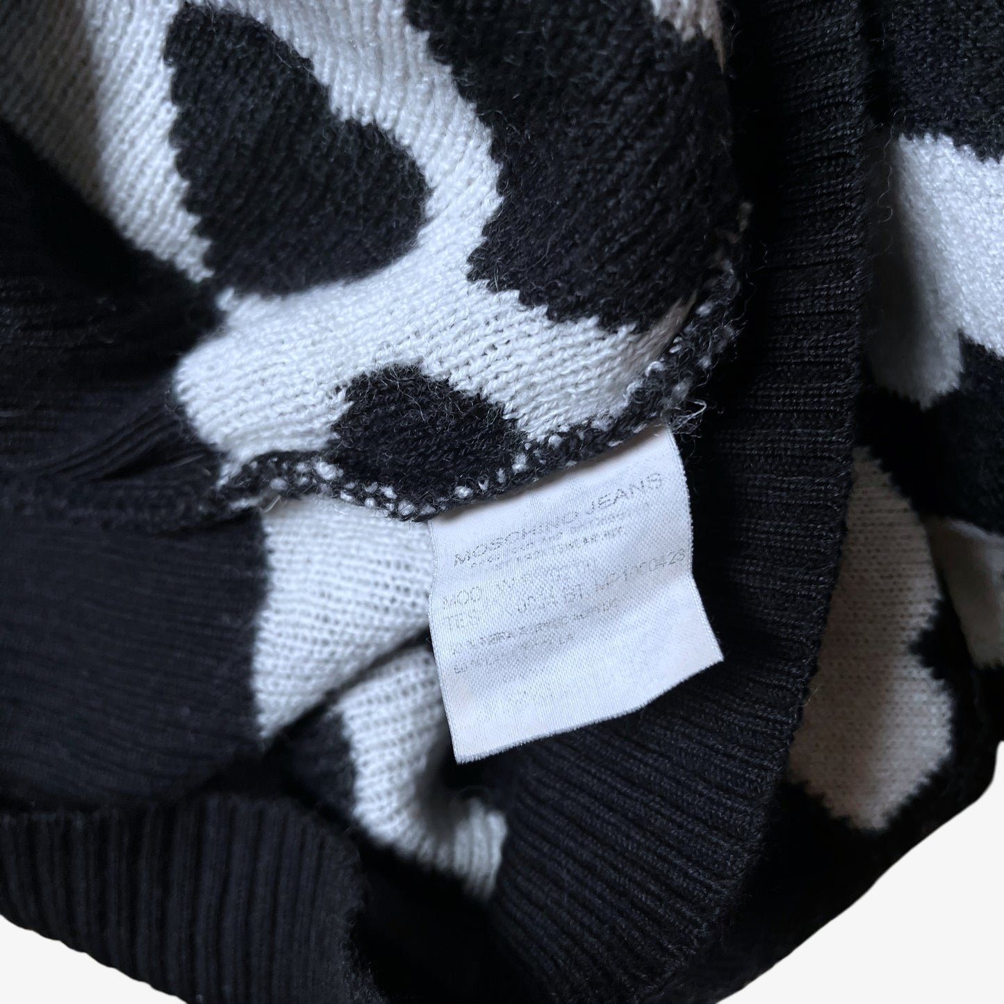 Inside label of vintage Y2K Moschino Jeans women's black and white v-neck wool jumper with heart pattern.