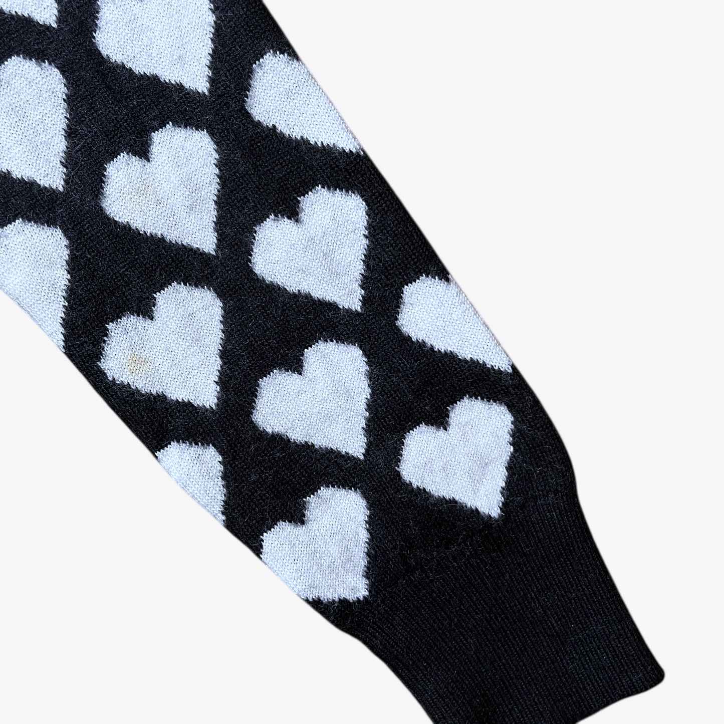 Sleeve of vintage Y2K Moschino Jeans women's black and white v-neck wool jumper with heart pattern.