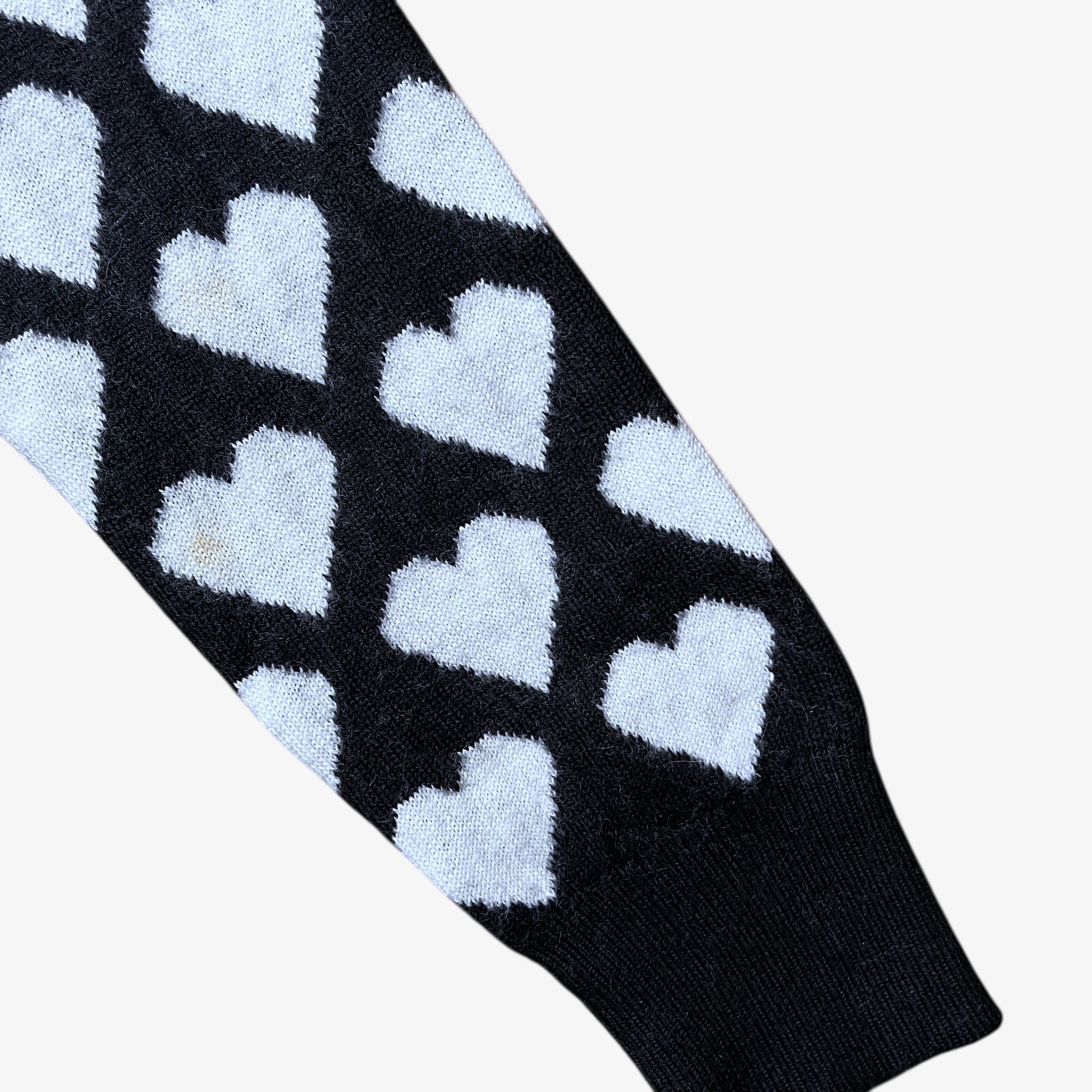 Sleeve of vintage Y2K Moschino Jeans women's black and white v-neck wool jumper with heart pattern.