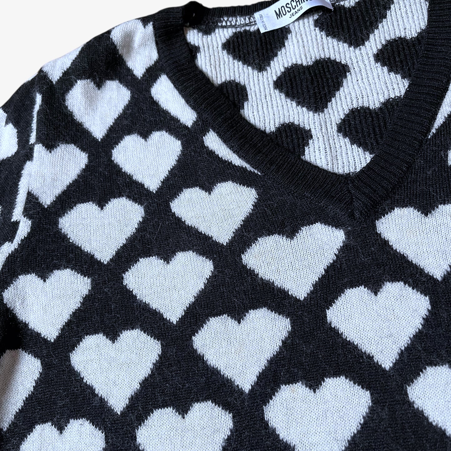 Close up of vintage Y2K Moschino Jeans women's black and white v-neck wool jumper with heart pattern.