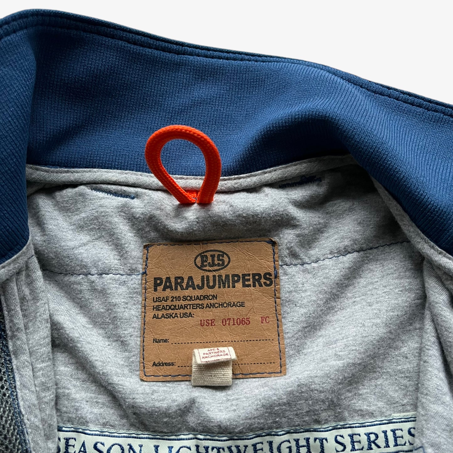 Parajumpers label stitched inside of vintage Y2K women's USAF 210 rescue squadron blue utility jacket.
