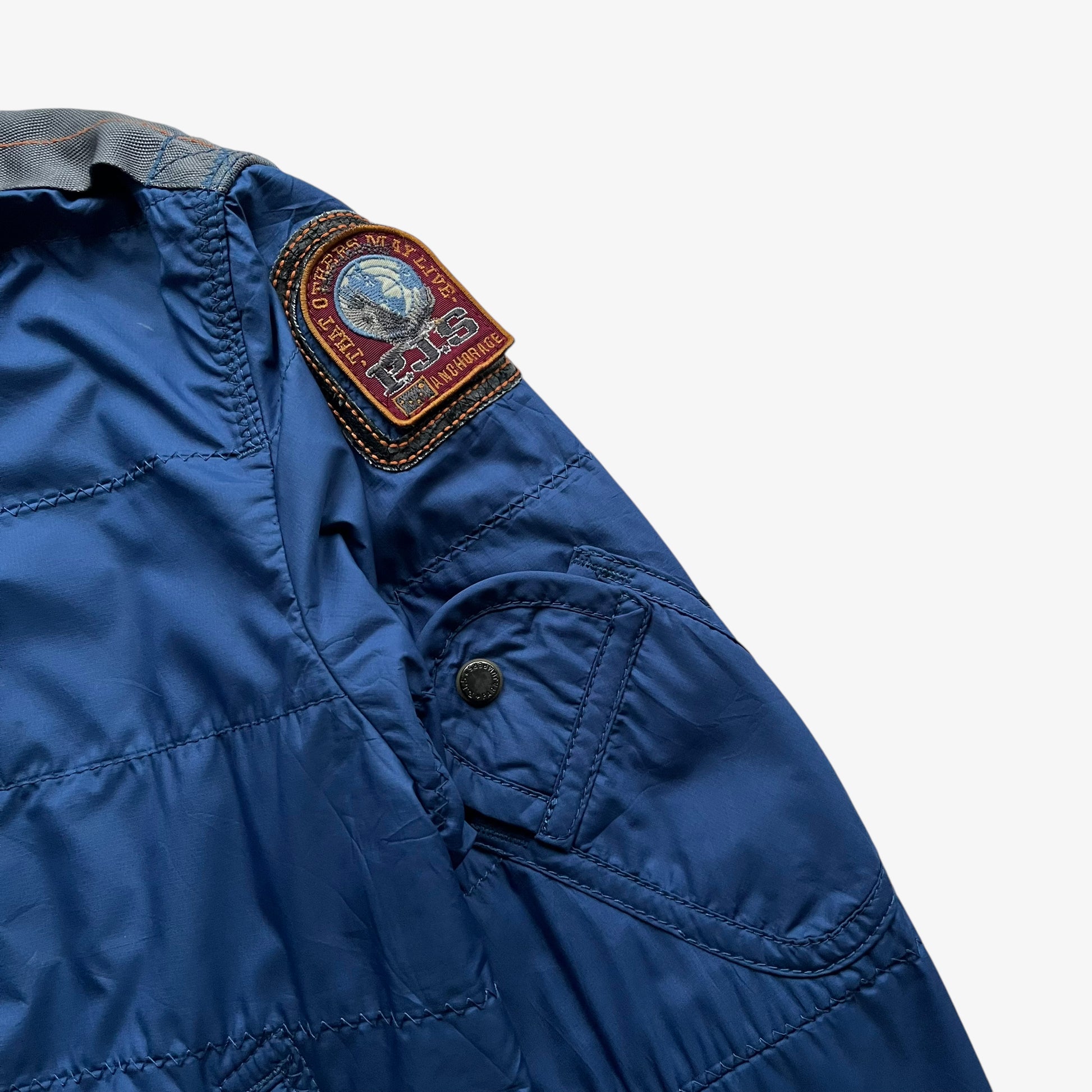Embroidered logo of vintage Y2K women's Parajumpers USAF 210 rescue squadron blue utility jacket.