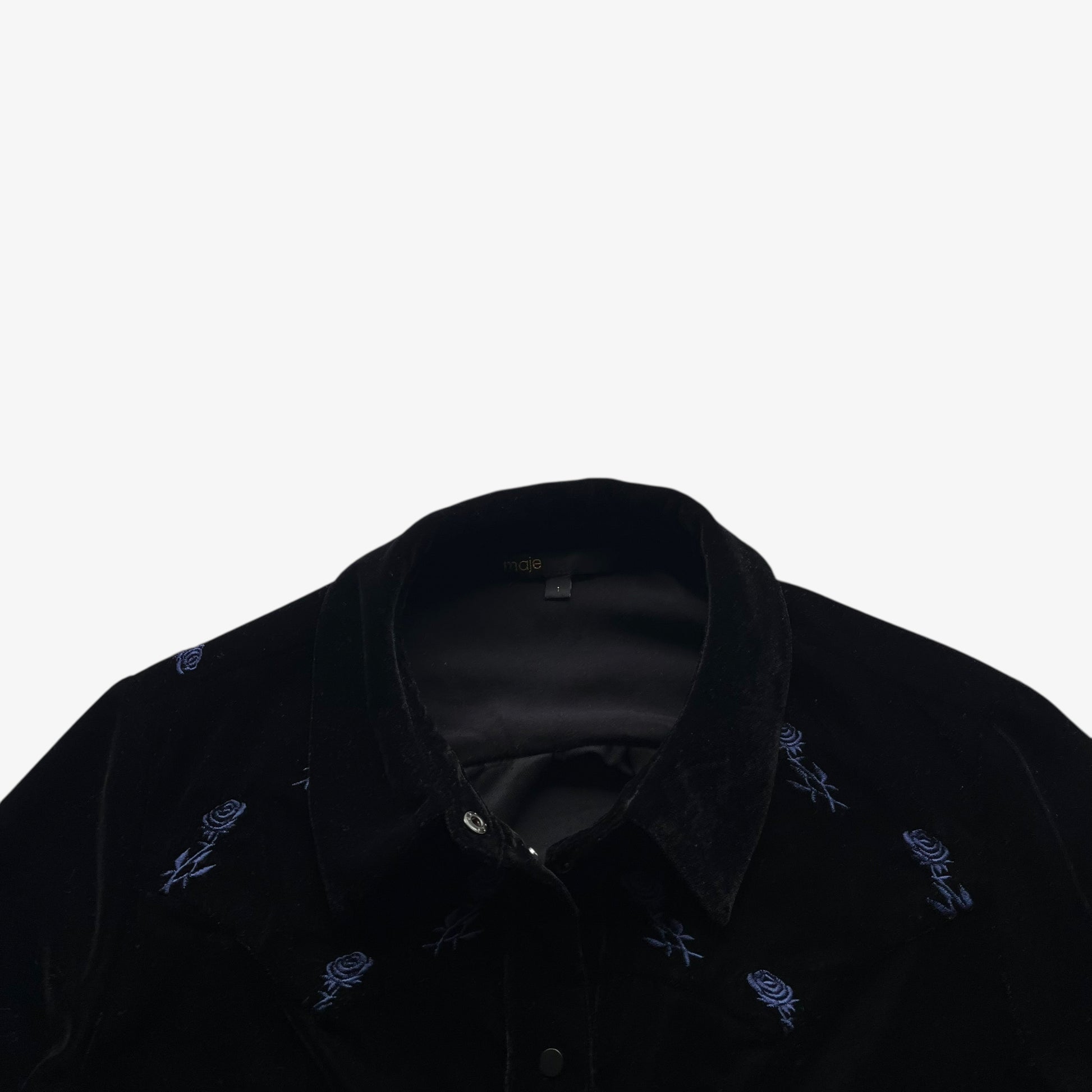 Close up of embroidered floral detailing on a women's Maje black velour shirt.