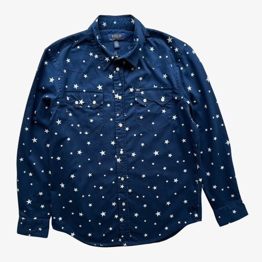 A navy women's long-sleeve button-up shirt with an all-over white star print, featuring two chest pockets and a classic collar, shown flat against a light grey background.