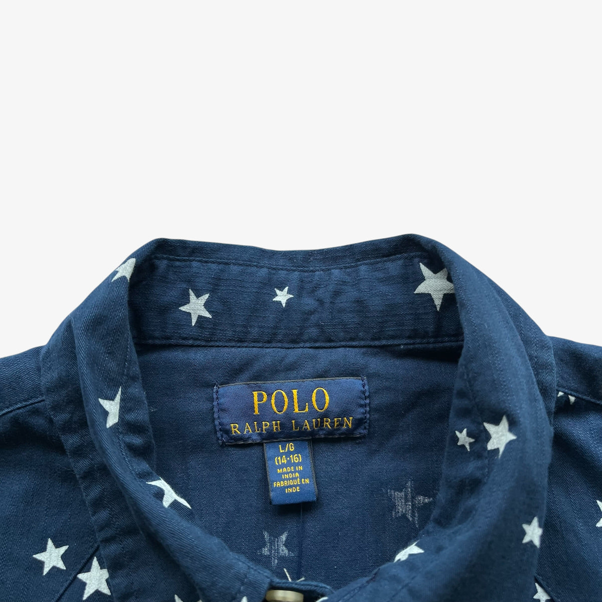Close-up of a navy blue Polo Ralph Lauren shirt with a white star pattern, showing the inner collar label.