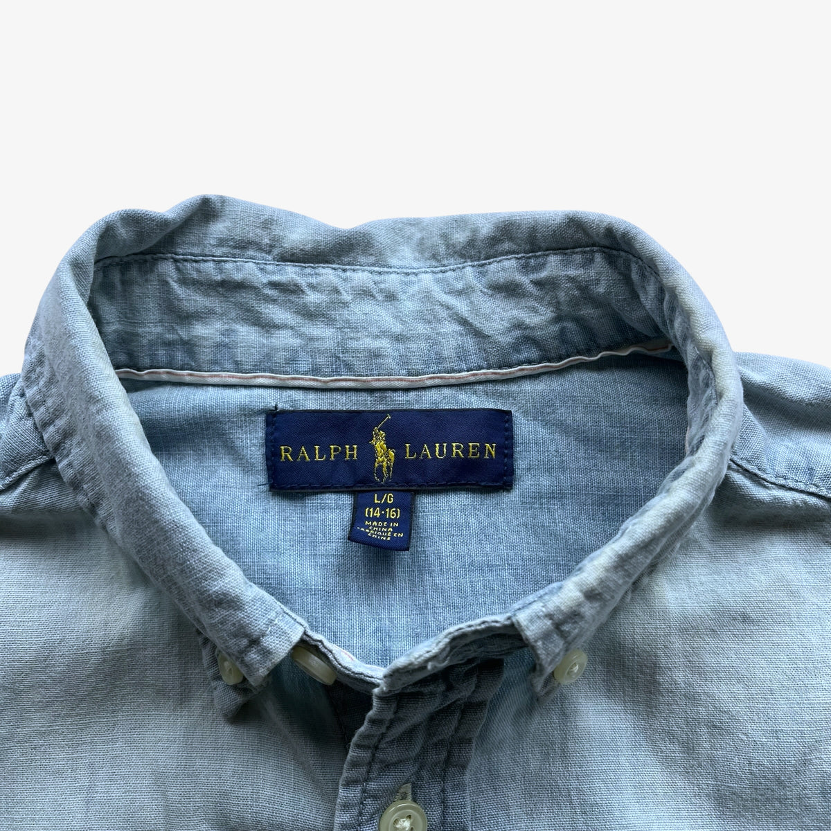 Close-up of a light blue chambray button-down shirt collar with a visible Ralph Lauren brand label.